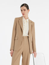 A lady wears a shirt and a camel blazer.